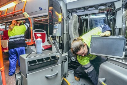 Dos trabajadoras limpian y desinfectan un autobús municipal para ponerlo a punto para los usuarios. ISRAEL L. MURILLO