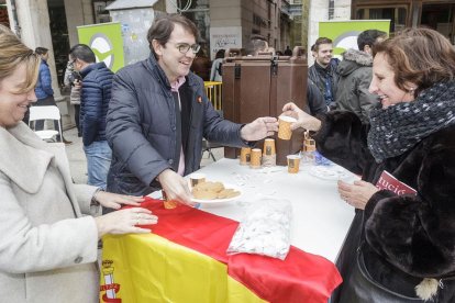 Alfonso Fernández Mañueco entrega un chocolate y unos bizcochos a una mujer, ayer, en la Plaza Mayor.-SANTI OTERO