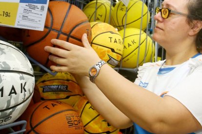 Una dependienta coloca un balón en un expositor en una tienda de deportes. ICAL