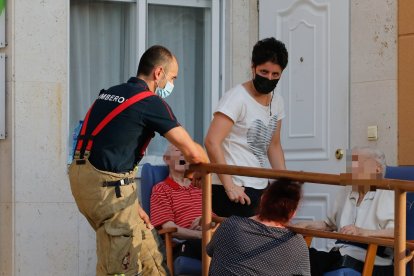 Varios residentes en el exterior del centro de mayores de Celada, asistidos por los bomberos y el personal sanitario. SANTI OTERO