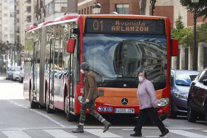 Dos personascon mascarilla cruzan por delante de un autobús en la calle Vitoria. RAÚL G. OCHOA