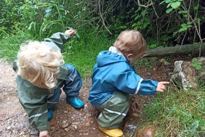 Dos hermanos juegan con piedras y palos en un río. ECB