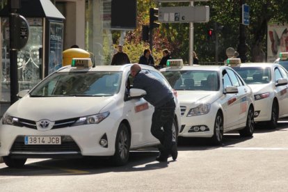 Un hombre charla con el conductor de un taxi en una parada de la capital.-SANTI OTERO