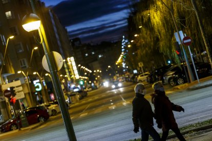 Dos viandantes caminan por una calle burgalesa iluminada por el alumbrado público. SANTI OTERO