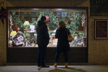 Dos personas observan el escaparate de una tienda de alimentación decorado ya con motivos navideños y artículos típicos de estas fiestas.-RAÚL G. OCHOA