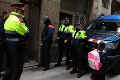 Los mossos saludando a una niña mientras esperan durante en la redada contra los narcopisos en la calle Sant Climent del Raval.-FERRAN NADEU