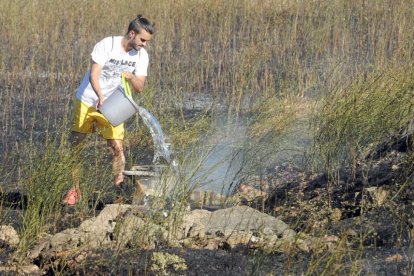 Un vecino colabora en la extinción del fuego en la barriada Yagüe.-ISRAEL L. MURILLO