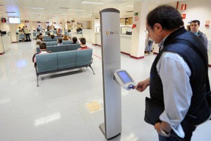 Un hombre saca el número para realizar operaciones en la oficina BAC del Ayuntamiento.-ISRAEL L. MURILLO