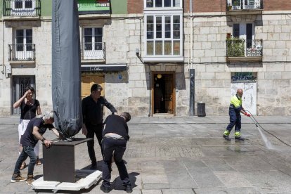 Varios trabajadores trasladan una sombrilla este martes en la plaza de La Flora. SANTI OTERO