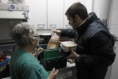 Un trabajador entrega una cesta de comida a una mujer.-SERGIO GONZÁLEZ