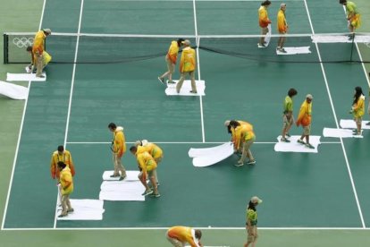 Voluntarios secan con toallas la pista central, en Río de Janeiro.-EFE / MICHAEL REYNOLDS