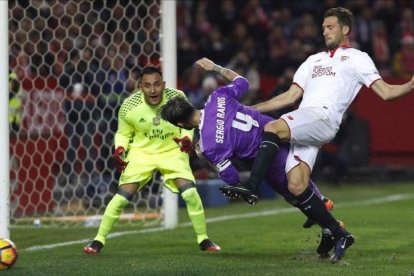 Keylor Navas observa el despeje de Sergio Ramos ante el sevillista Franco Vázquez.-EFE / JULIO MUÑOZ