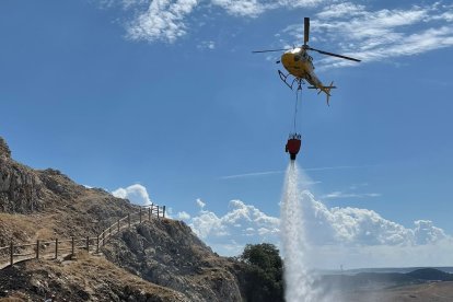 Un helicóptero echa agua sobre la ladera del castillo de Monasterio de Rodilla. ECB