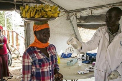 Un trabajador sanitario comprueba el estado de varias personas en la frontera de Nimule, en Uganda.-AFP / AKUOT CHOL