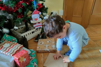 Un niño recién levantado abre sus regalos en la mañana de Reyes. ECB