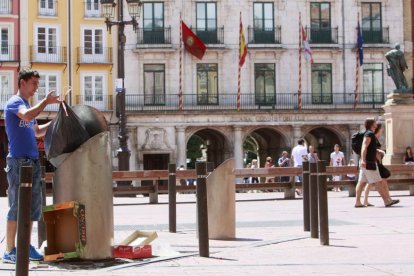 Una persona deposita basura en un contenedor soterrado de la Plaza Mayor.