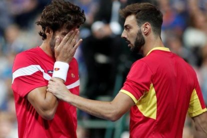 Feliciano López se toca la cara tras recibir el impacto de una bola, junto a Granollers, en Lille.-BENOIT TESSIER (REUTERS)