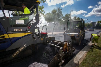 Operarios trabajando en el Camino de Casa la Vega en la campaña de asfaltado de este verano. TOMÁS ALONSO