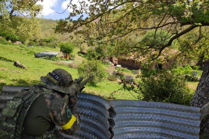 Un jugador de airsoft agazapado detrás de un obstáculo en una partida. LA FUNDICIÓN