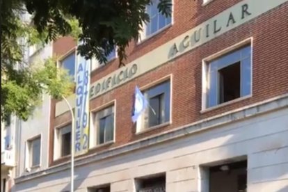 El emblema de Hogar Social Madrid ondea en una de las ventanas del nuevo edificio okupado, las antiguas oficinas de la Editorial Aguilar. /-PERIODICO