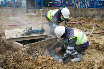 Dos obreros trabajan en la remodelación de la calle Valle de Mena en el polígono de Villalonquéjar. TOMÁS ALONSO