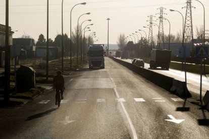 Un ciclista circula por la avenida López Bravo en el polígono industrial de Villalonquéjar. TOMÁS ALONSO