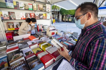 Un lector ojea un título en una de las casetas de la feria. SANTI OTERO