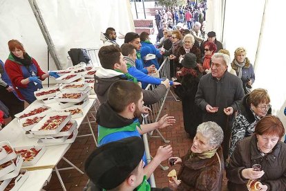 Varios voluntarios reparten los pinchos entre los vecinos.-RAÚL G. OCHOA