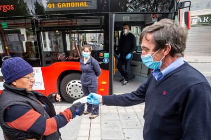 Un conductor de autobús entrega una mascarilla a un pasajero. SANTI OTERO