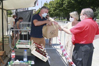 Una pareja compra unas cajas de cerezas, ayer, en el paseo de la Sierra de Atapuerca. RAÚL G. OCHOA