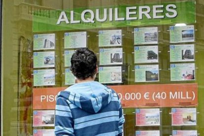 Un joven observa un escaparate con anuncios de alquileres. S. O.