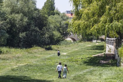 Varias personas pasean por la riberas del río Arlanzón en el centro de la ciudad.