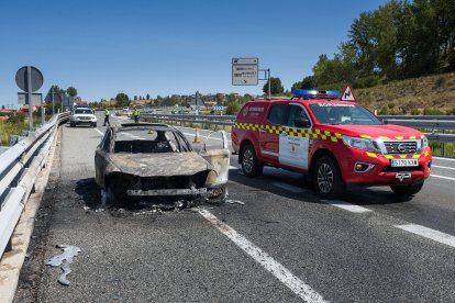 Imagen de un vehículo de Bomberos junto un coche calcinado en la A-62.