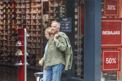 Dos personas pasan por delante de una tienda en la capital burgalesa en plenas rebajas de la temporada de verano.