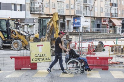 Unos vecinos cruzan un paso de peatones junto a la señalización de calle cortada.