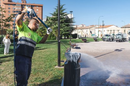 Un operario de Urbaser muestra como se limpian las pintadas vandálicas sobre una papelera, en el entorno de la Real y Antigua de Gamonal.