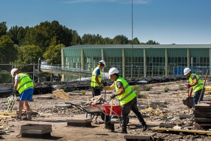 Varios obreros trabajan en la cubierta del edificio de acceso y vestuarios de las piscinas de El Plantío.