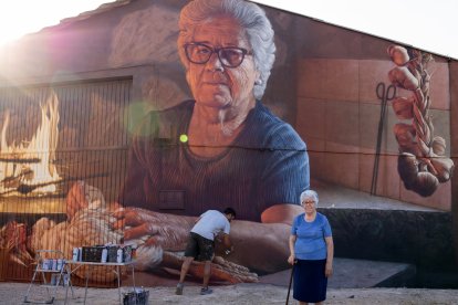 Christian da los últimos retoques al mural con Liduvina delante.