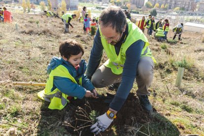 Un adulto planta un árbol con un niño en el entorno de Las Rebolledas.