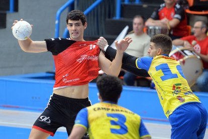 Ernesto López es agarrado cuando trata de jugar el balón.