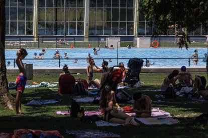 Varias familias disfrutan de la zona de sombra en las piscinas municipales de verano de El Plantío.