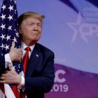 El presidente Donald Trump abrazando una bandera de su país.-REUTERS