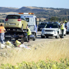 Unos operarios limpian la carretera junto a uno de los coches implicados.-ICAL