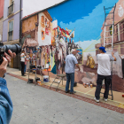 Un hombre hace una fotografía al mural mientras los artistas trabajan en él. TOMÁS ALONSO