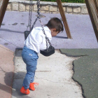 Un niño juega en un columpio con el suelo roto.-L. VELÁZQUEZ