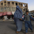 Una mujer afgana vestida con un burka agarra de la mano a su hijo al cruzar una calle en Herat, Afganistán, este jueves.-EFE / JALIL REZAYEE