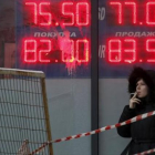 Una mujer, ante un panel que muestra el cambio del rublo ante el euro y el dólar, en Moscú.-REUTERS / SERGEI KARPUKHIN
