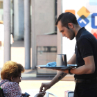 Un camarero da el cambio a una mujer en la terraza de un establecimiento.-ISRAEL L. MURILLO