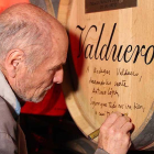 Antonio López escribe una dedicatoria en una de las barricas de la bodega.-ECB