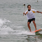 La antorcha olímpica surfea en las playas de Río.-AP / CHARLIE RIEDEL